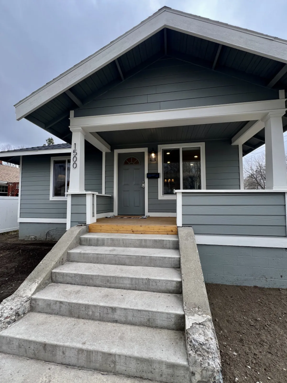 This image shows the front door of The Winston, framed by a classic roof overhang and porch railing. The entryway is inviting, giving a sense of arrival and hinting at the walkable, welcoming nature of the neighborhood. The porch creates a visual bridge between the home and the vibrant streets beyond.