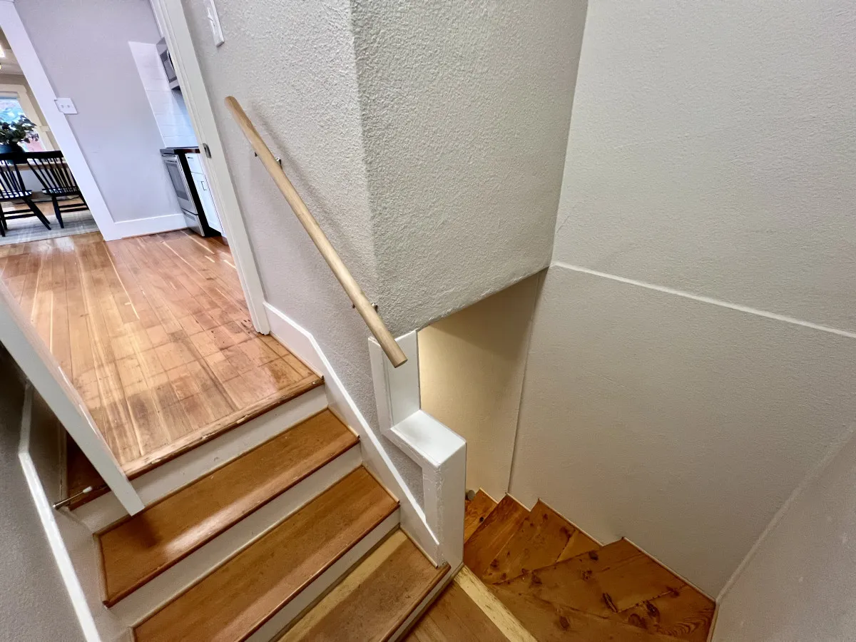 This image captures an interior staircase with a handrail and an adjoining doorway, symbolizing the connection between the home's multiple levels and versatile living areas. The warm and welcoming design invites exploration between floors, tying together the different spaces for group activities or retreats.