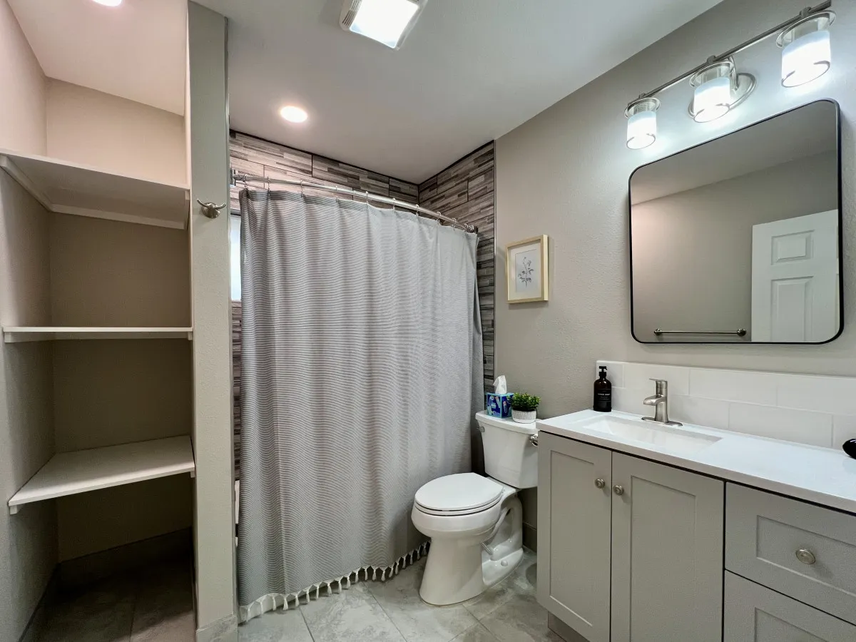 A bright bathroom scene with a modern vanity, large mirror, and fresh shower curtain. The space feels clean, inviting, and ideal for personal care routines.